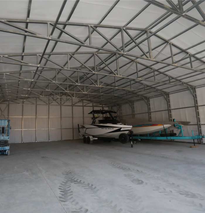 Spacious custom metal carport interior by Quality Metal Carports, Inc. featuring a boat on a trailer to demonstrate high-clearance boat storage capabilities.