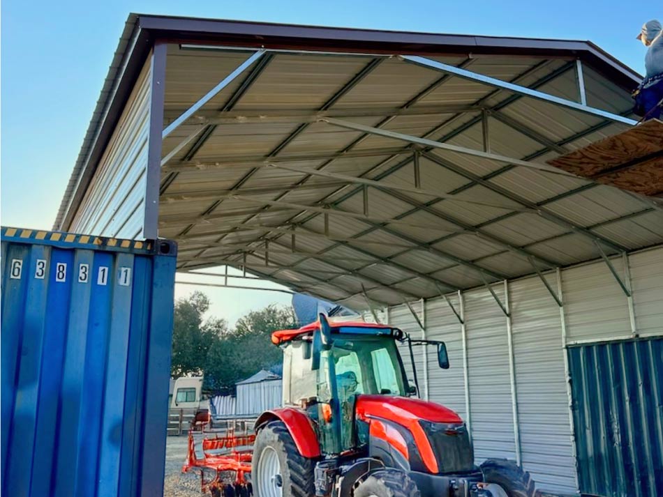 an open metal carport covering a agricultural tractor